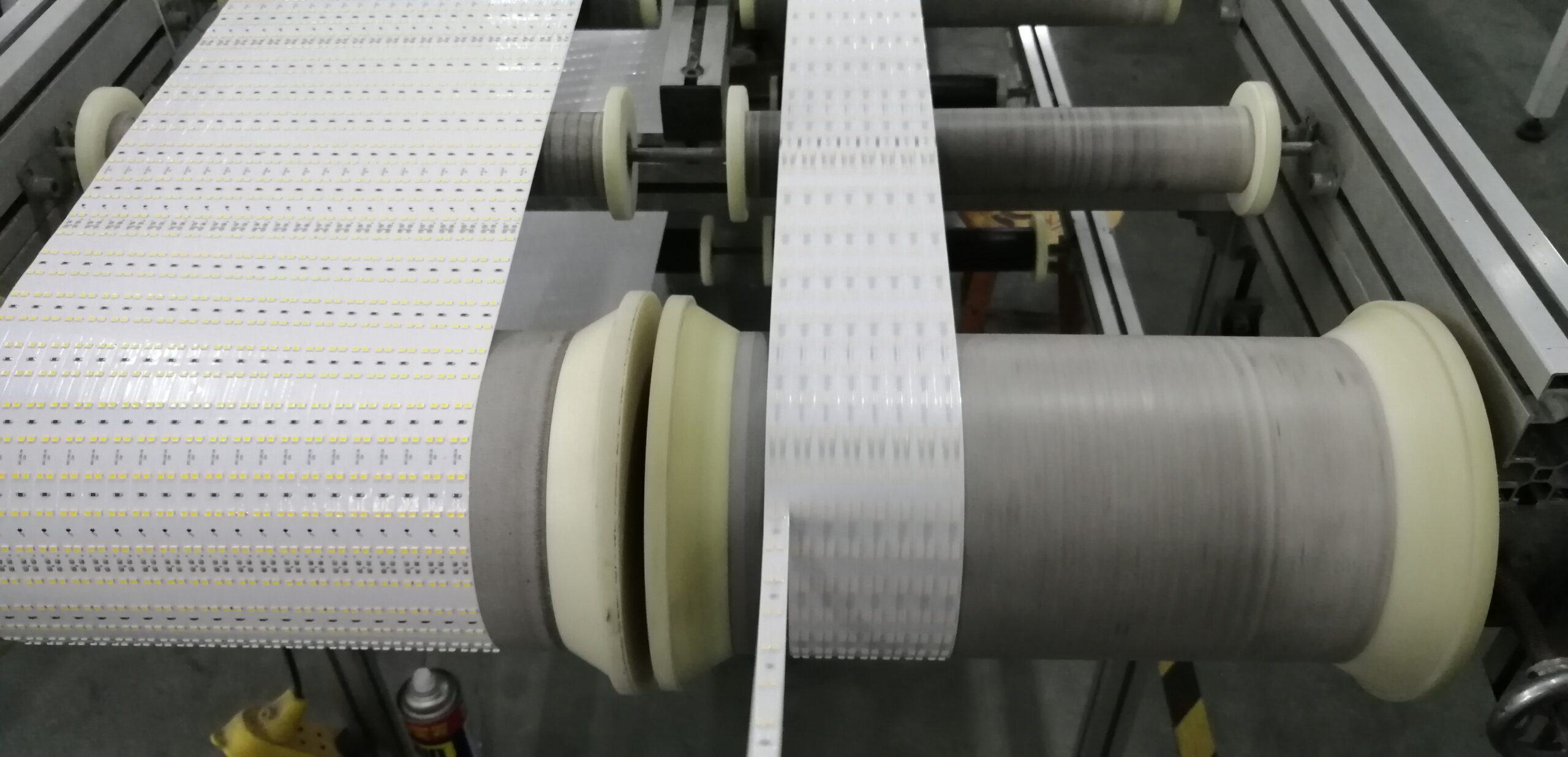 Automated machinery performing slitting of full PCB panels into individual strips and re-reeling them into finished rolls.