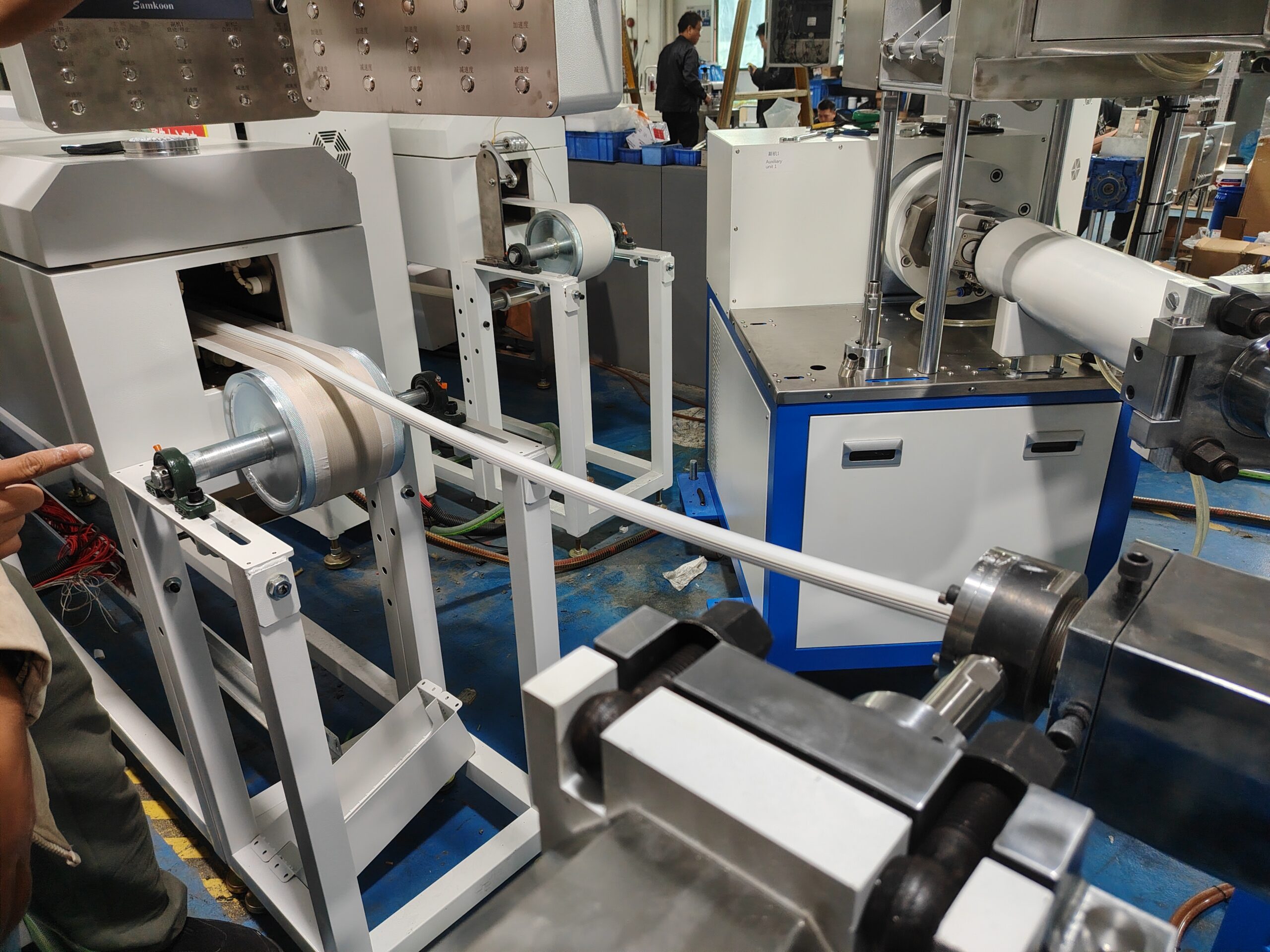 Silicone neon flex strip being extruded from the machine head and immediately fed into the tunnel oven for curing.