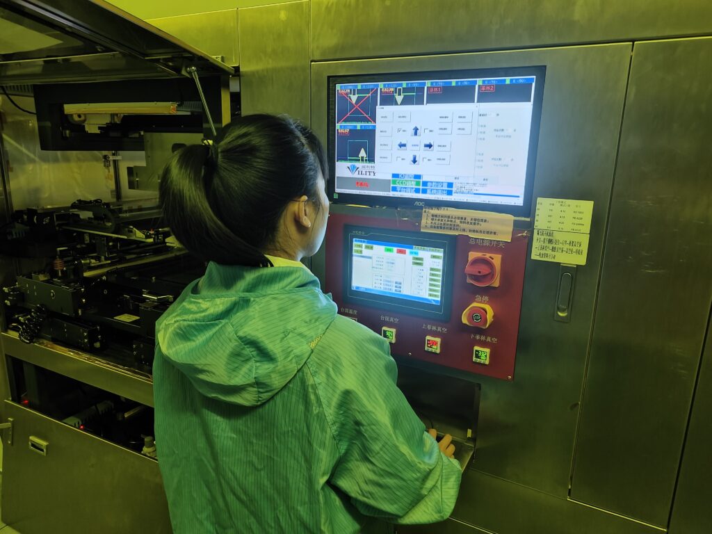 Factory worker editing the coating scheme/program on the automated conformal coating machine for LED strips.