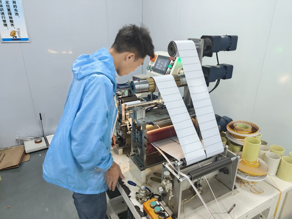Technician managing the automated slitting and re-reeling process for flexible LED strip PCBs, preparing them for packaging.