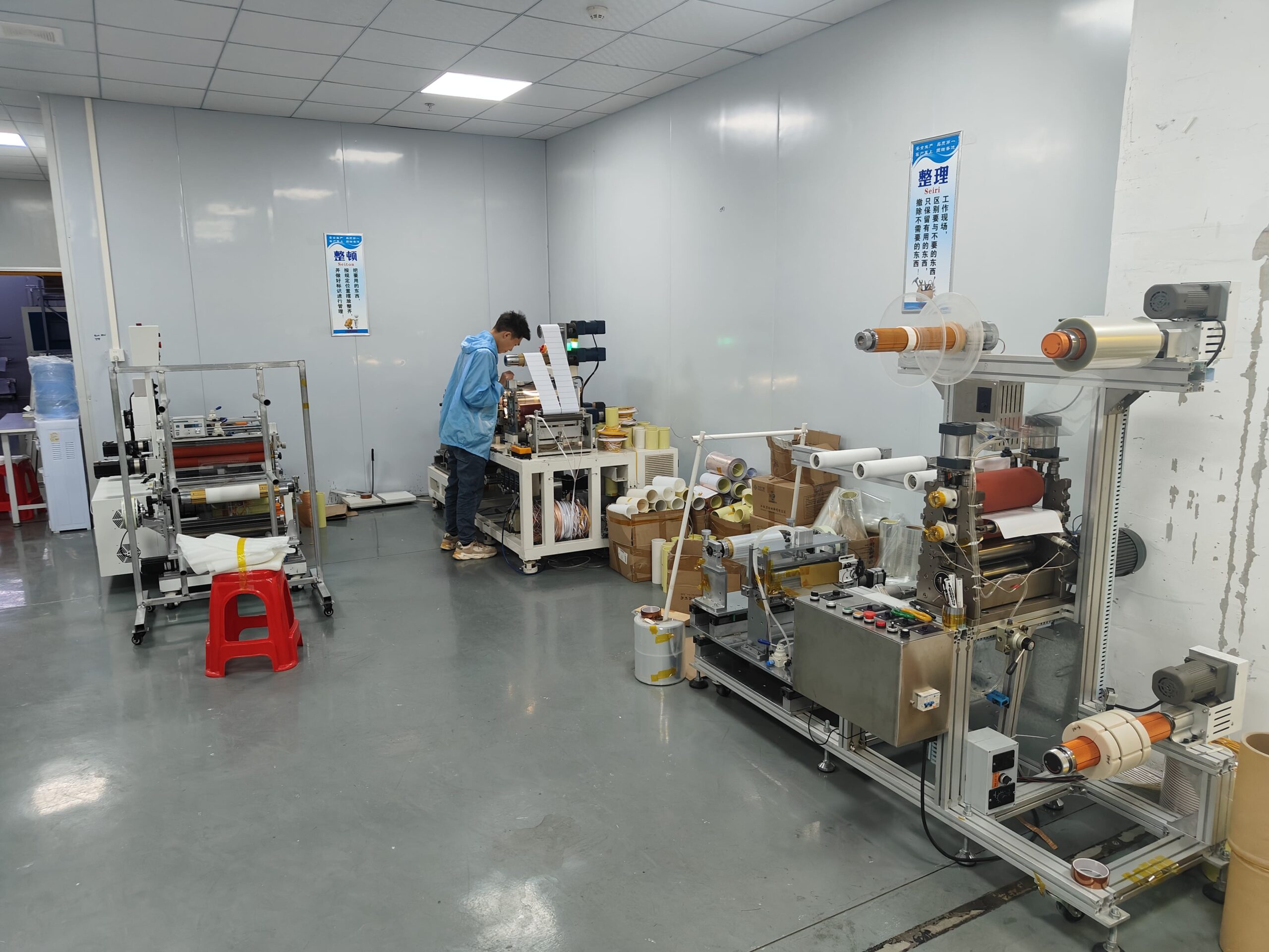 Factory worker operating the machine to slit large PCB panels into strips and re-reel them into finished rolls.